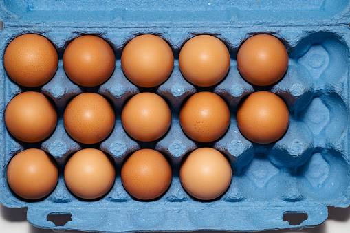 top view freerange fresh eggs in blue recycled carton crate. Farm texture soft light closeup