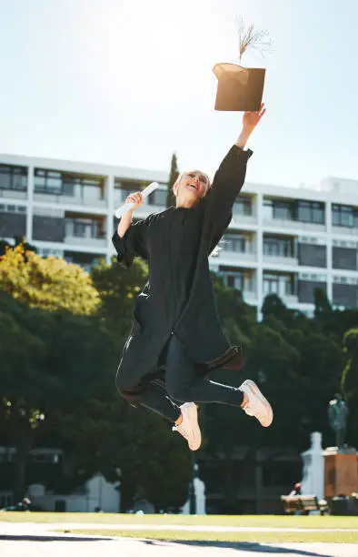 Photo of Woman graduation, jump and celebrate at college, school or university with certificate in sunshine. Student graduate, scholarship or diploma in success, celebration or education while happy at campus