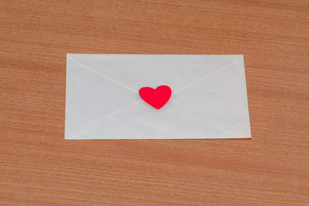 istock Love letter for Valentine's Day inside a white envelope closed and sealed with a red heart on a wooden background by a lover. 1459039932
