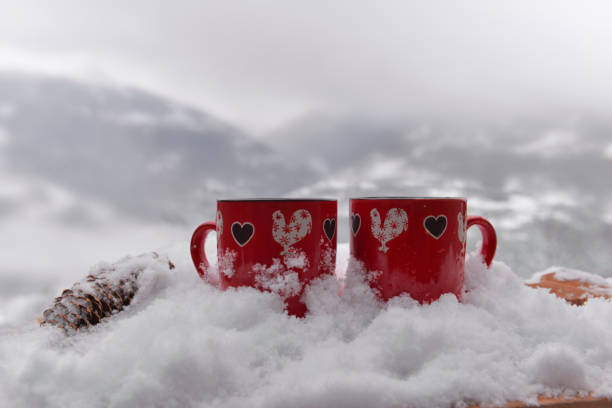 istock two red mugs with heart shaped on the snow and mountain background 1459039940