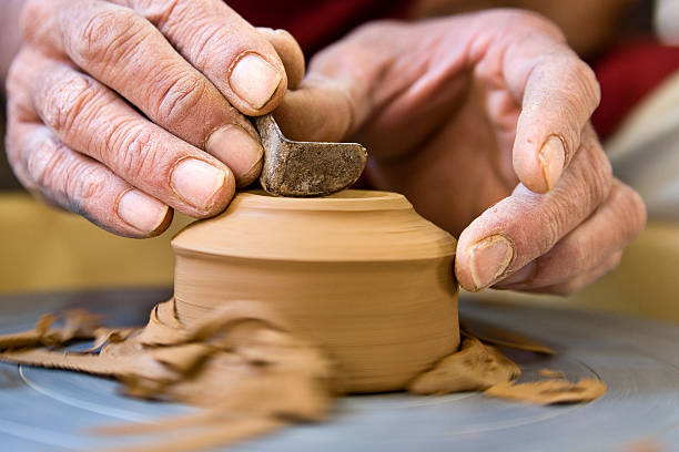 Potter shaping a cup base on  spinning wheel stock photo