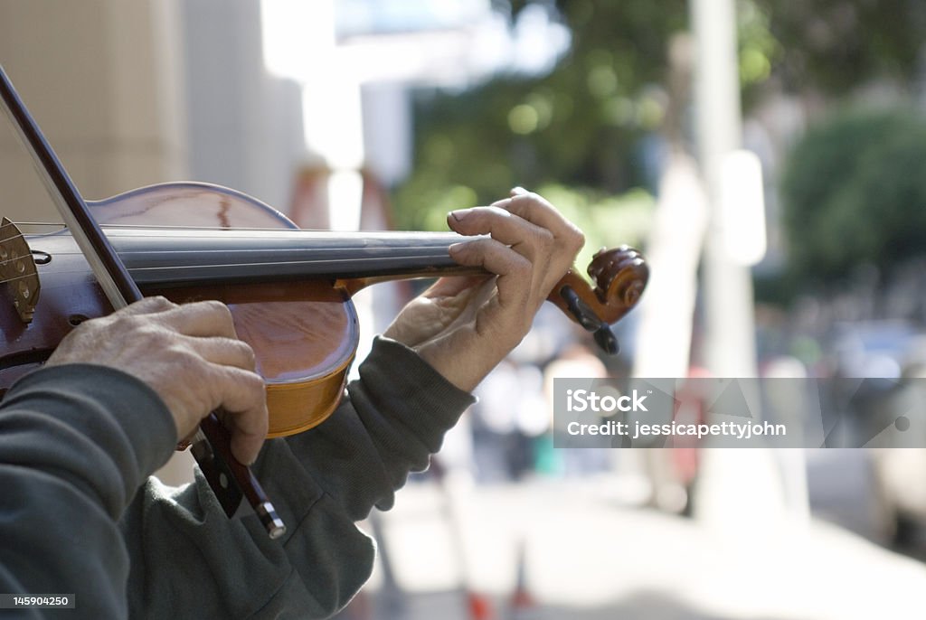 City Sonnet While strolling downtown Los Angeles I came across a homeless man playing the saddest sonnet on such a bright day.  Shot with small depth of field so that the street could blur while focusing on his dirty hands on his violin.  Art comes from all places. City Life Stock Photo