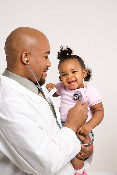 Male pediatrician examining baby girl. stock photo