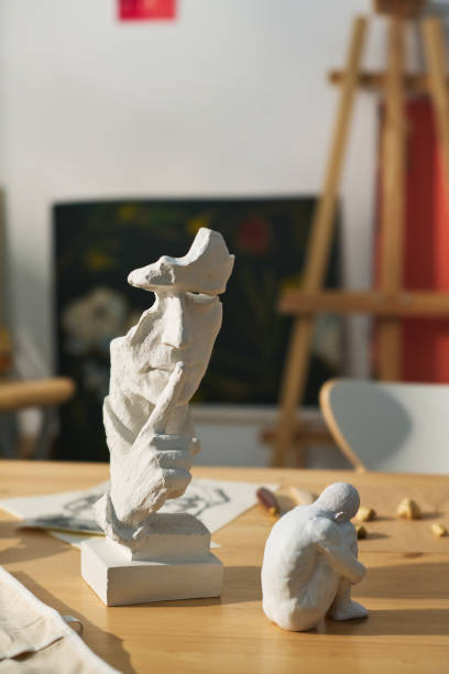 istock Two small clay or gypsum figurines on wooden table in craft studio 1459044017
