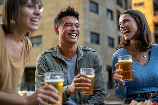 Happy friends drinking beer at brewery pub dehor, friendship lifestyle concept with young millenials people enjoying time and having fun together at outside pub