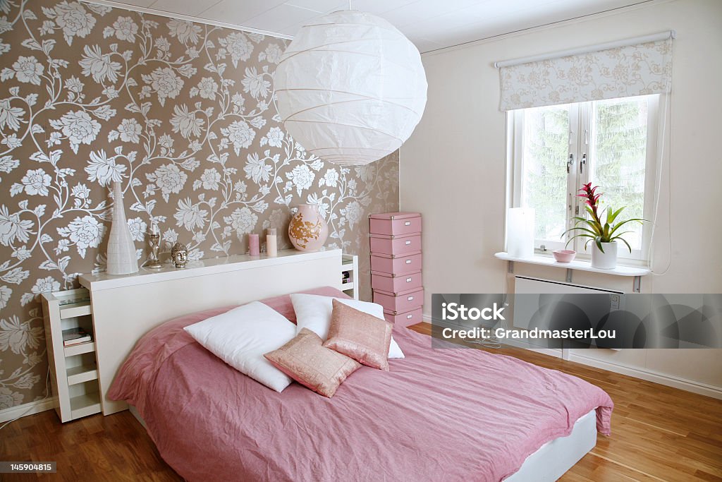 A beautiful bedroom with floral wall and pink bed sheets Modern Scandinavian bedroom. Bedroom Stock Photo