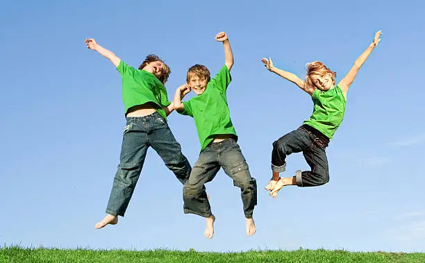 happy healthy group of smiling children or kids jumping for joy