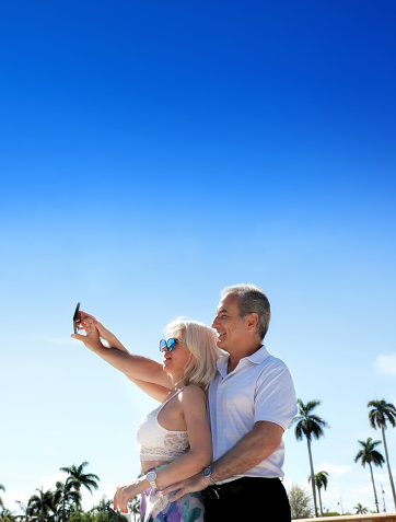Outdoor portrait of well dressed middle age caucasian adult woman and man couple at park over sunny sky in Florida