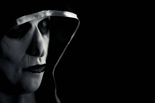 Teenage girl wearing a dark hood, looking at camera.