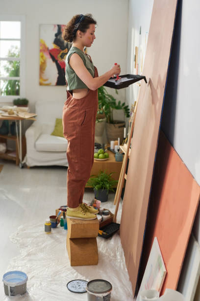 istock Side view of young creative female painter creating new masterpiece 1459059719