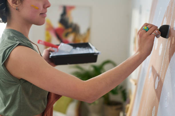 istock Close-up of young creative woman making white paint prints on panel 1459059811
