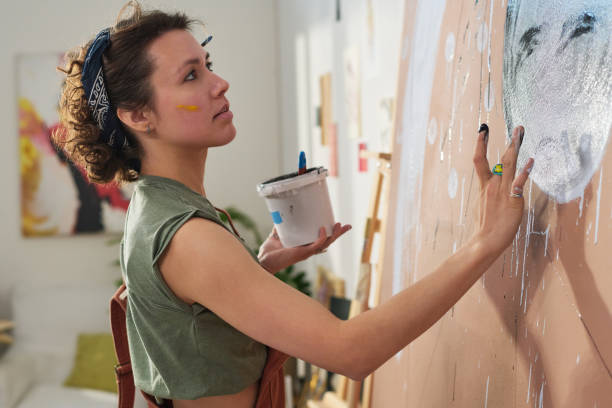 istock Youthful creative girl painting new masterpiece with hands on large panel 1459059921