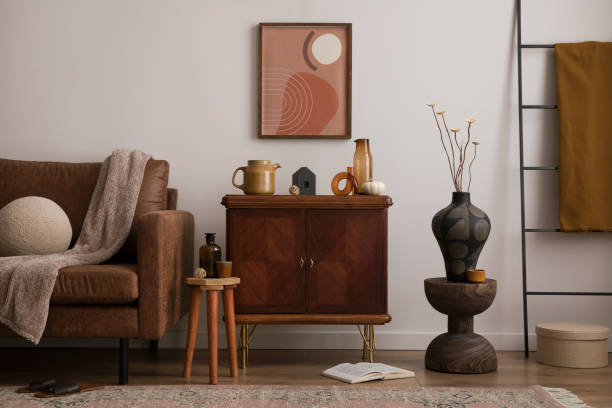Interior design of cozy living room interior with mock up poster frame, brown sofa, stylish sideboard, vase with dried flowers, round pillow, books, plaid, pumpkin and personal accessories. Home decor. Template. diseño interior del acogedor interior de la sala de estar con marco de póster de maqueta, sofá marrón, aparador elegante, jarrón con flores secas, almohada redonda, libros, plaid, calabaza y accesorios personales. decoración del hogar. plantilla.