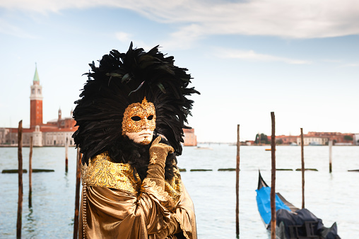 Venice, Italy - March 4, 2019  Carnevale di Venezia 2019 and participant with colorful costume by the water