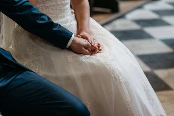 istock bride and groom holding hands during wedding ceremony in church 1459063429