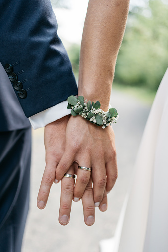 The man gently holds the bride's hand with a beautiful golden wedding ring. Enlarged image of newlyweds' hands. Wedding concept. The groom gently touches the bride