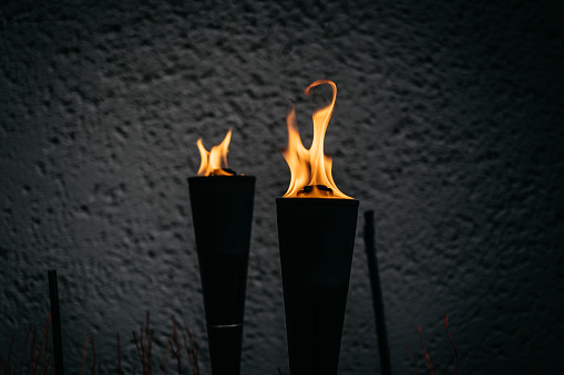 two burning torches in the night in front of a house wall