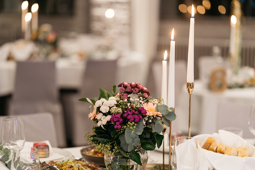 wedding decoration in the evening with burning candles, flower decoration and bread basket