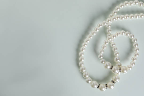 istock Elegant pearl necklace and bracelet on white table, top view. Space for text 1459064853