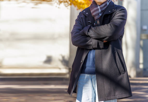 A man wearing a coat in the beautiful sunlight filtering through the trees