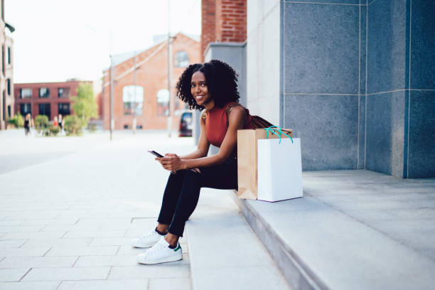 istock Smiling black lady surfing on cellphone 1459067160