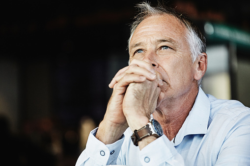 Man in smart casual clothing sits thinking hard about solutions.