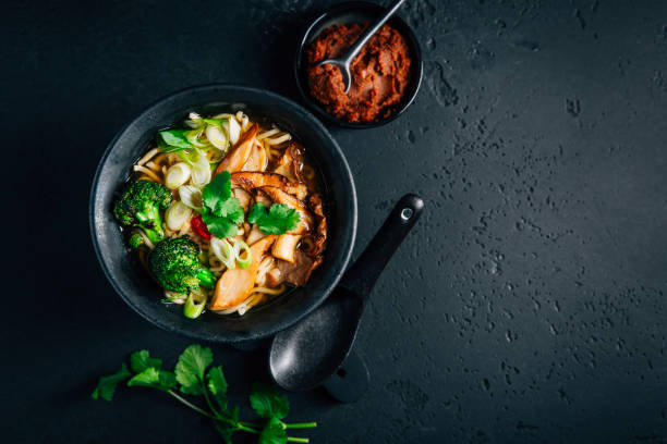soupe miso ou ramen végétalienne aux champignons et légumes sur fond noir - tofu chinese cuisine vegetarian food broccoli photos et images de collection