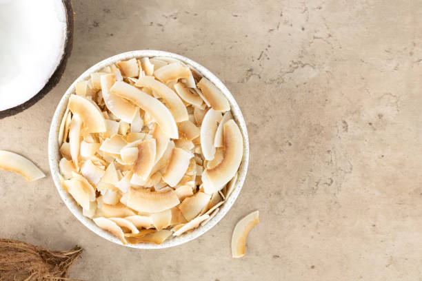 istock Coconut chips or coconut flakes in a white bowl and fresh coconuts on a beige background. Top view. Copy Space. Healthy snacks. Coconut dessert. 1459079614