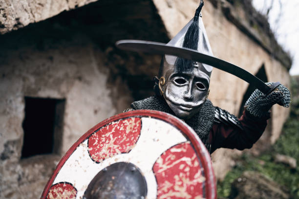 Portrait of unrecognizable medieval warrior with a helmet, sword and shield