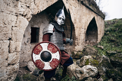 Portrait of unrecognizable medieval warrior with a helmet, sword and shield