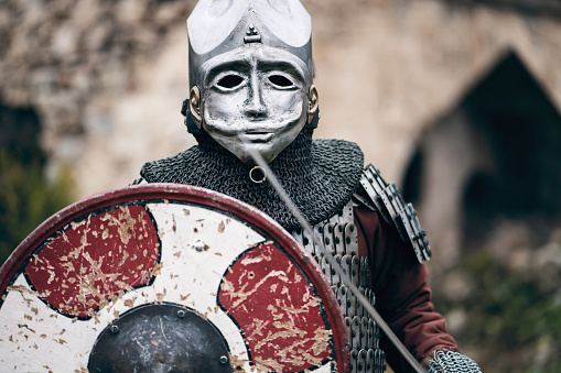 Portrait of unrecognizable medieval warrior with a helmet, sword and shield