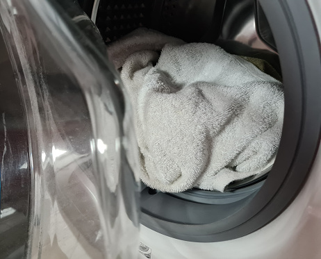 Open drum of washing machine and washing white linens. Unloading the washing machine and cleaning