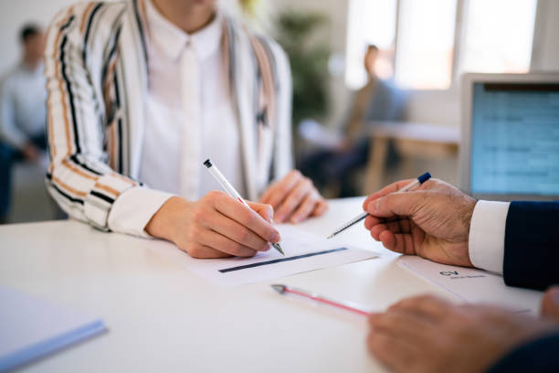 female candidate, fills in an application form while having a job interview with a recruiter - endorsing business application form filling imagens e fotografias de stock