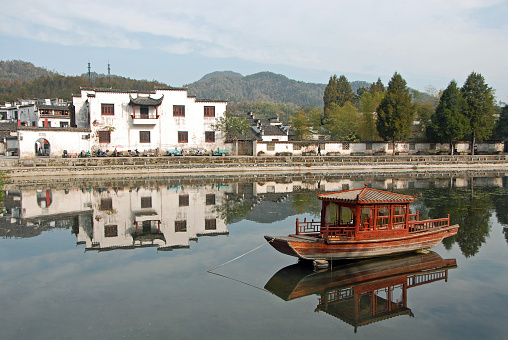 Xidi Ancient Town in Anhui Province, China. A house in the old town seen across Ming Jing Lake with boat