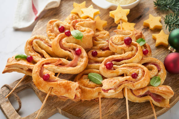 istock Christmas or New Year appetizer. Christmas tree shape puff pastry buns with cheese and ham. Group of Christmas tree shapes on wooden board. Festive idea for Christmas or New Year dinner. Top view. 1459088955