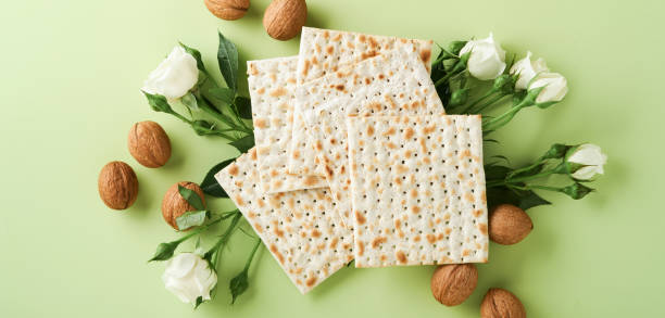 istock Passover celebration concept. Matzah, red kosher wine, walnut and spring beautiful rose flowers. Traditional ritual Jewish bread on light green background. Passover food. Pesach Jewish holiday. Banner 1459088963