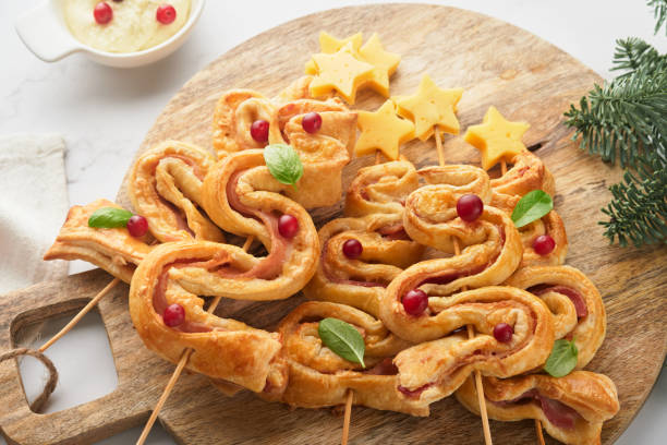 istock Christmas or New Year appetizer. Christmas tree shape puff pastry buns with cheese and ham. Group of Christmas tree shapes on wooden board. Festive idea for Christmas or New Year dinner. Top view. 1459089172
