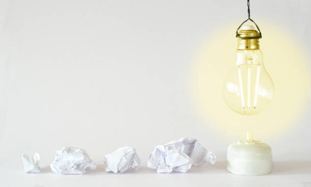 Fresh ideas or business transformation concept with crumpled paper balls and a light bulb, start up, success, teamwork and creativity business concept stock photo