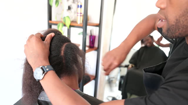 Close up hairdresser uses comb to part hair