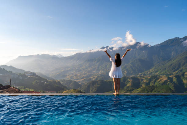 Young woman traveler relaxing at sky pool and looking at the beautiful nature landscape with blue sky and mountains in Sapa, Vietnam Young woman traveler relaxing at sky pool and looking at the beautiful nature landscape with blue sky and mountains in Sapa, Vietnam luxury hotel stock pictures, royalty-free photos & images