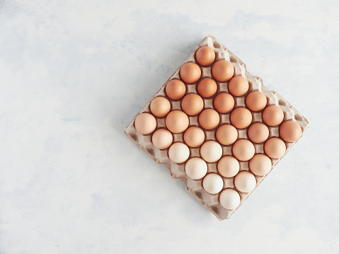 carton egg box with many brown eggs in diferents colours and degradient tones top view