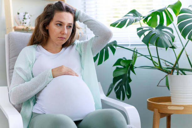 Young woman suffering from nausea and headache during pregnancy stock photo