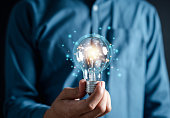 Hand man holding illuminated lightbulb, idea, innovation and inspiration with glowing virtual brain, smart intelligent creativity with bulbs, Motivation and innovation concept.