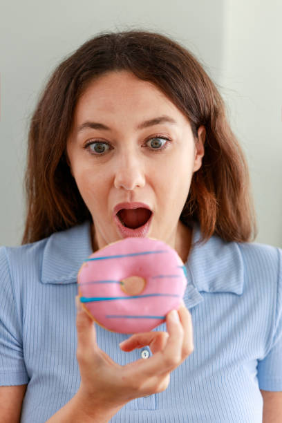 istock Young woman eating pink chocolate chips donut 1459105272