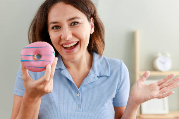 istock Beautiful young woman with pink chocolate chips donut 1459105338