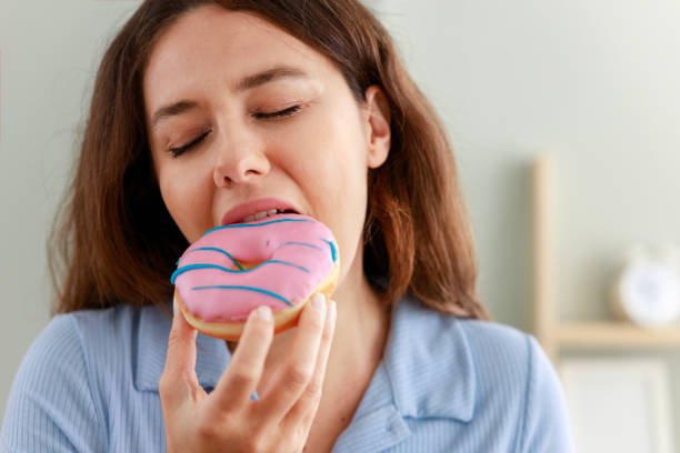 istock Young woman eating pink chocolate chips donut 1459105358