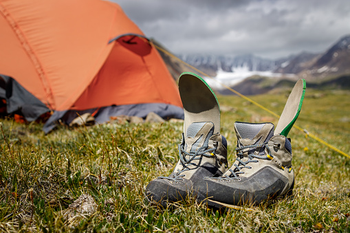 Trekking boots are drying in the mountain camp. Boots in focus, background blurred.