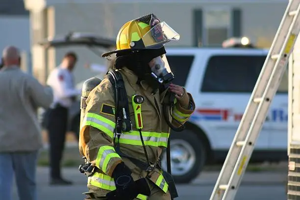 Female Firefighter preparing herself before she enters a burning building.