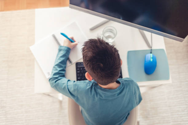 istock Distance learning online education. Back to school. Cute kid boy studying at home with computer and doing school homework. Thinking child sitting at table with computer. 1459109748