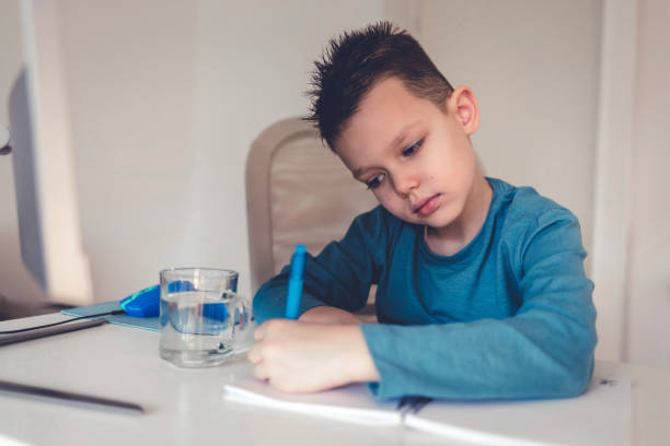 istock Young boy in the living room sitting at desk doing homework. 1459111419